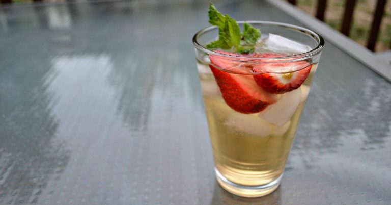 glass of ice tea with ice cubes, strawberries and mint leaves