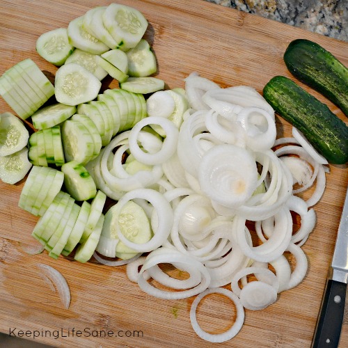 overhead view of cucumbers and onions sliced on a cutting board