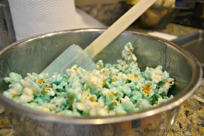 stainless steel bowl with blue candied popcorn with rubber scrapper