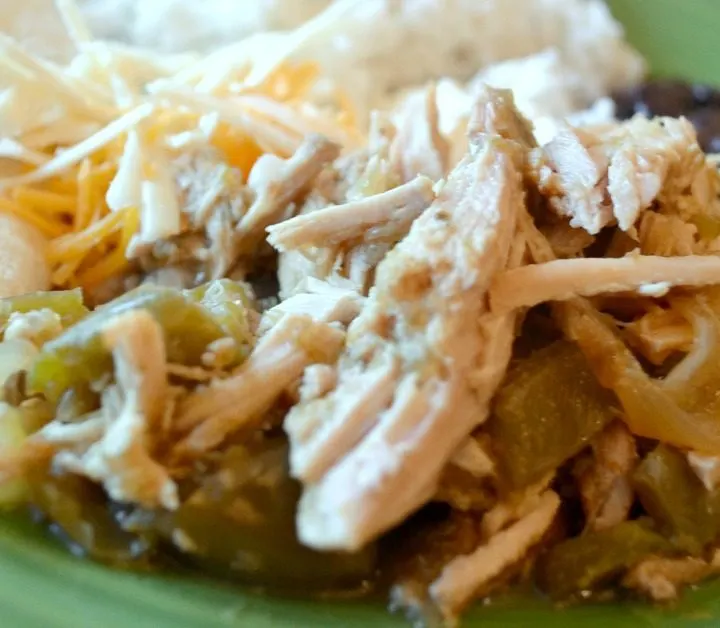 rice, tortillas, black beans, shredded cheese and pork salsa verde on green plate.