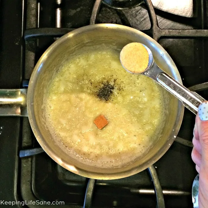 overhead view on boiling cream of chicken mixture with measuring spoon with garlic powder
