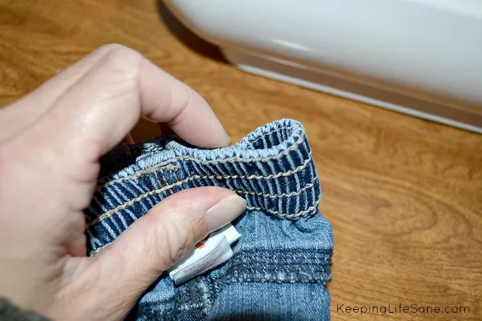 Hand pinching waistband of jeans waist