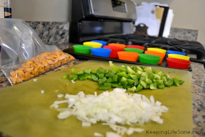 preparing to make meatloaf with diced peppers and onions on yellow cutting board with colorful liners in the background