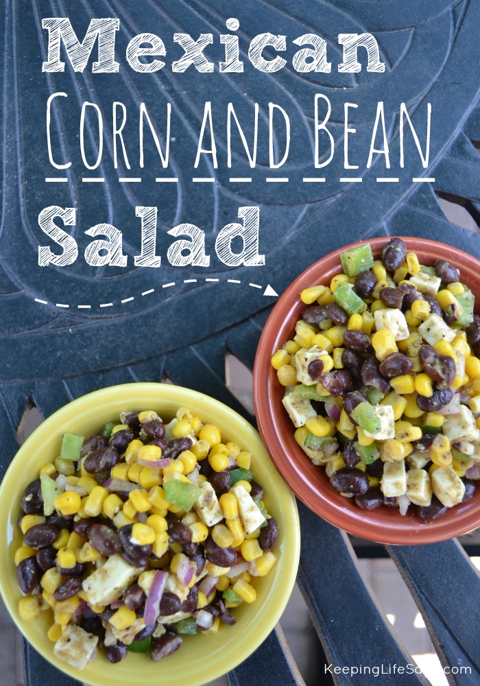 overhead view of two bowls of Mexican corn black bean salad in a red and yellow bowl on an outside iron table