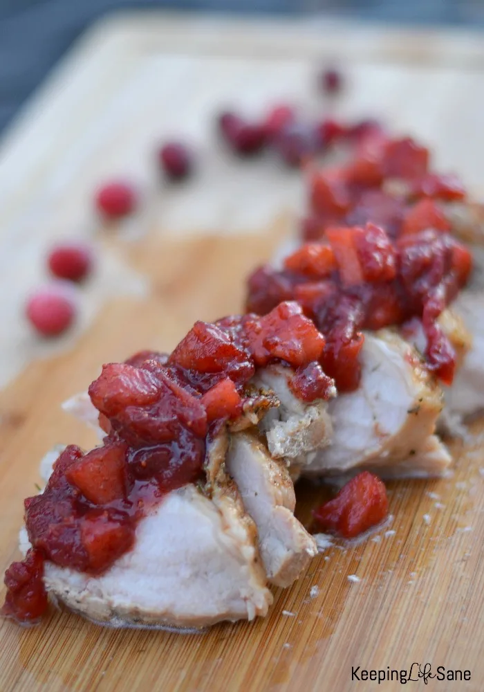 sliced pork loin on cutting board with cranberry apple salad on top