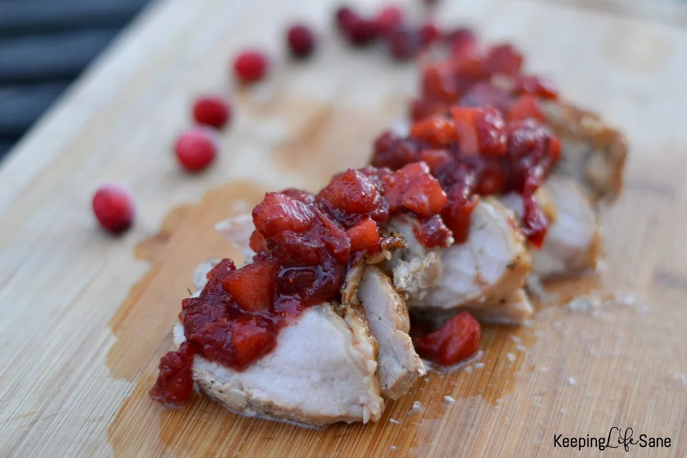 sliced pork loin on cutting board with cranberry apple salad on top
