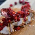 sliced pork loin on cutting board with cranberry apple salad on top