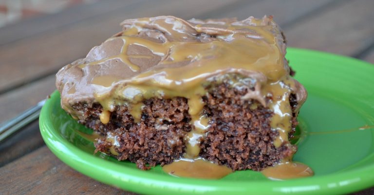 close up of chocolate cake with chocolate icing with caramel syrup oozing out on green plate