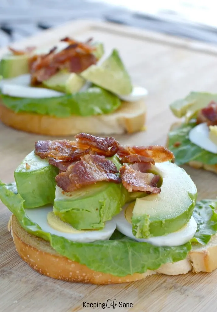 toast with lettuce, hard boil eggs, gree avocados with bacon on top