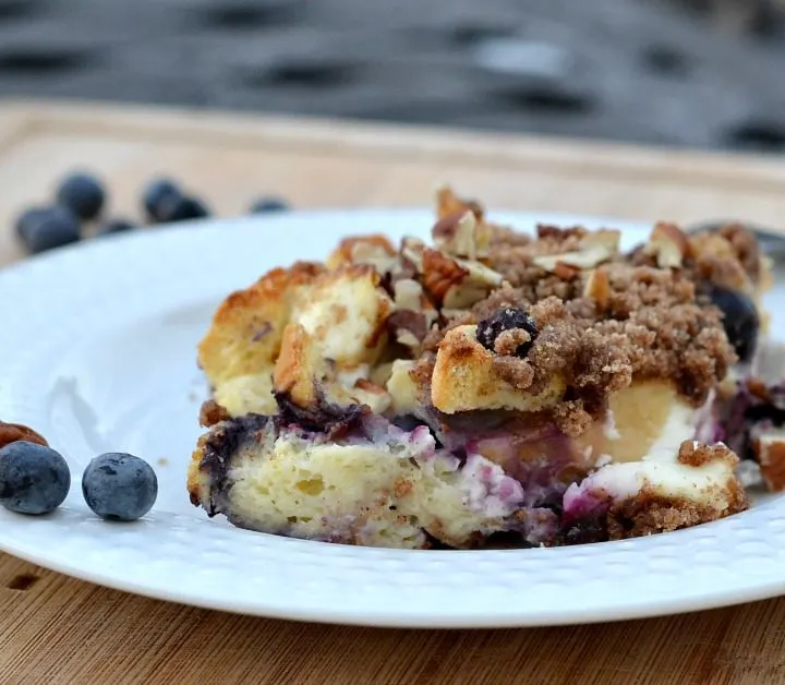 white bowl on cutting board with french toast casserole with blueberries