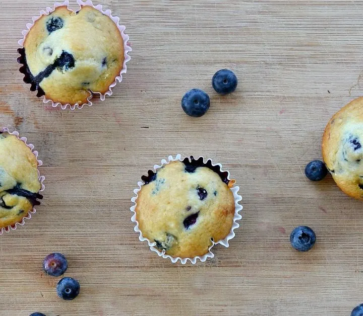 overhead view of eggless blueberry muffin on a wooden cutting board