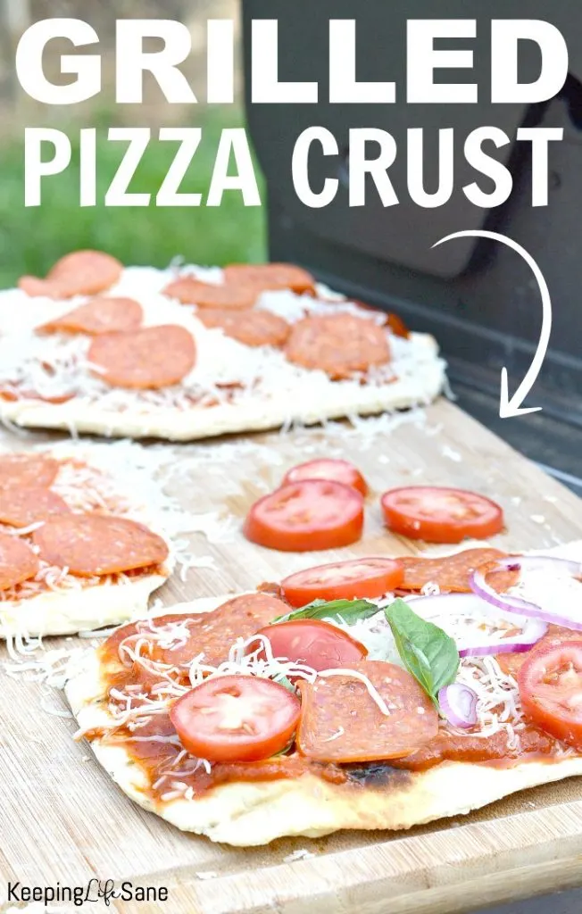 grilled pizza crust with tomatoes, basil pepperoni and cheese on a cutting board