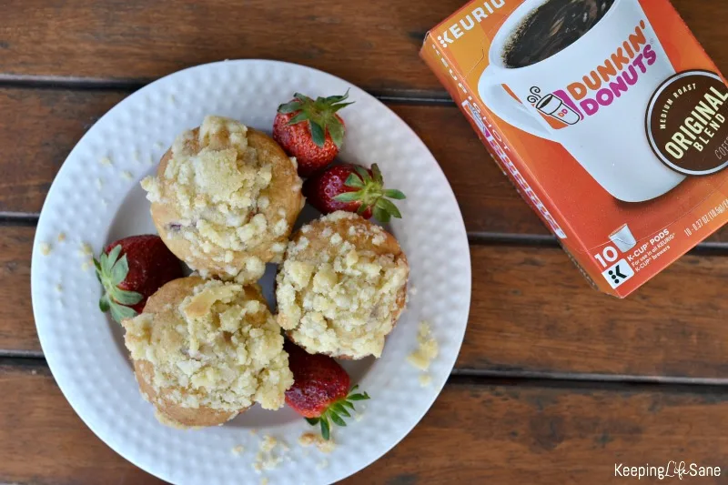 overhead view of white plate with three strawberry streusel muffins with real red strawberry off to the sides and a package of Dunkin Donuts coffee pods