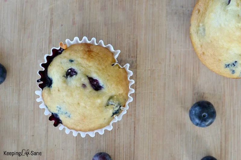 overhead view of eggless blueberry muffin on a wooden cutting board