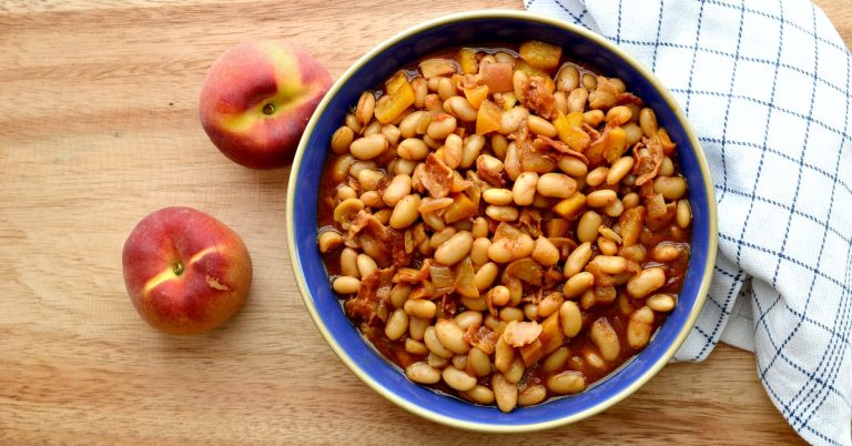 overhead view of peach baked beans in blue bowl on cutting board