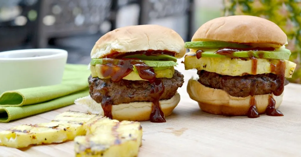 two grilled sliders with pineapple avocado and lots of dripping barbecue sauce