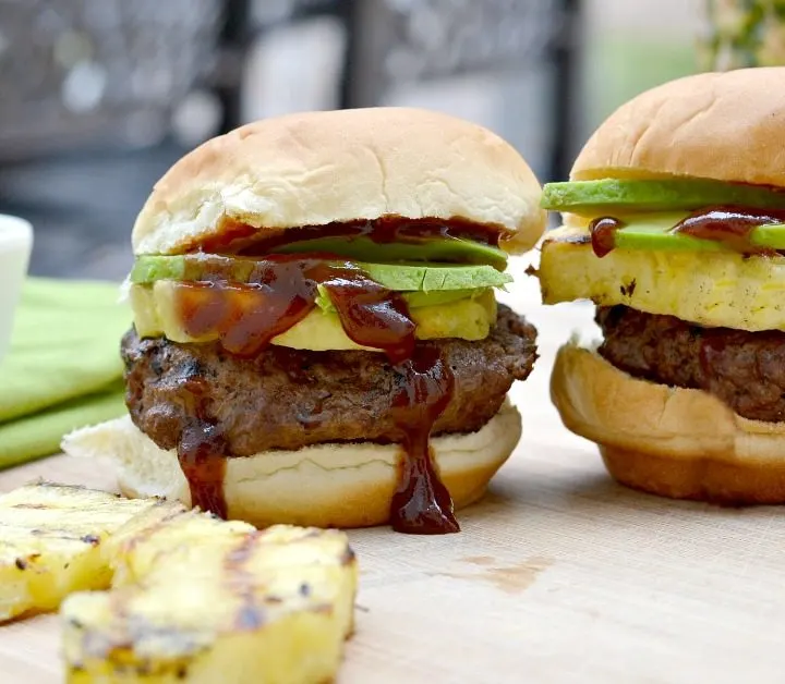 two grilled sliders with pineapple avocado and lots of dripping barbecue sauce