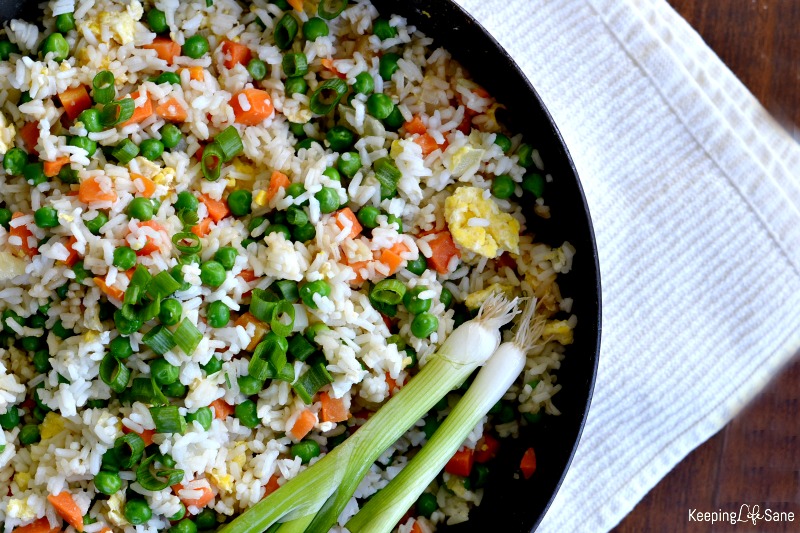 Overhead view of wok with vegetable fried rice with green onions laying on the side of the pot