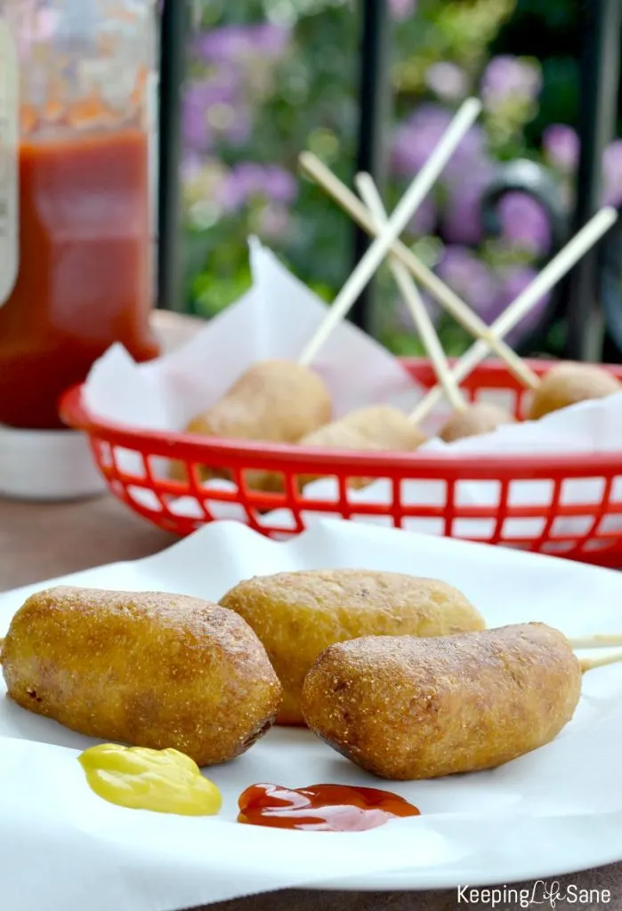 overhead view of homemade corn dogs on white parchment paper and mustard and ketchup