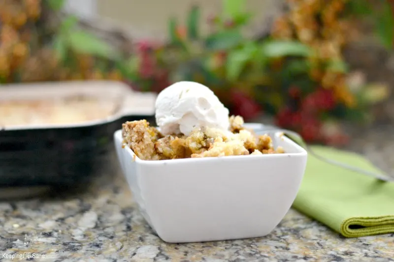 square bowl with pumpkin pecan dump cake with scoop of vanilla ice cream on kitchen counter with green napkin