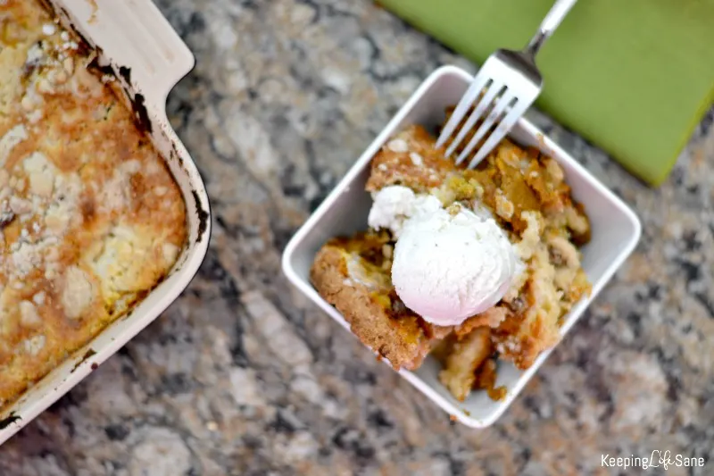 OVerhead view of pumpkin Pecan Dump Cake in white bowl with vanilla ice cream on top.