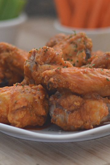Closeup of pile of crispy baked buffalo wings on a white plate