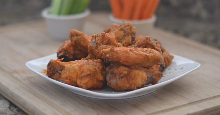 Closeup of pile of crispy baked buffalo wings on a white plate
