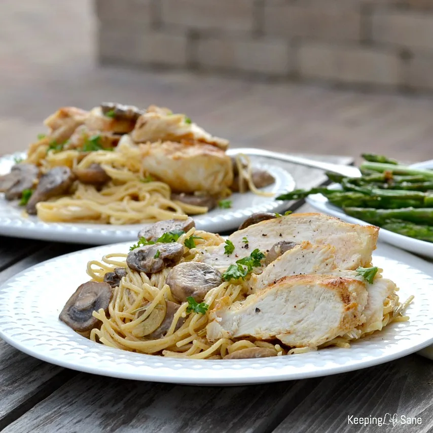 chicken, pasta and mushrooms on white plate with asparagus on the side
