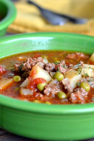 ground beef tomato soup in green bowl on a wooden table