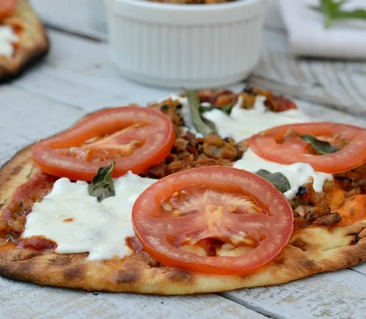 ground chicken on pizza with Mozzarella, basil leaves and tomato slices