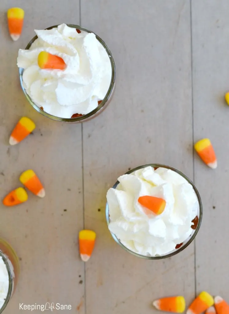 overhead view of candy corn jello cups with yellow and orange jellos with whipped cream on top in clean glasses