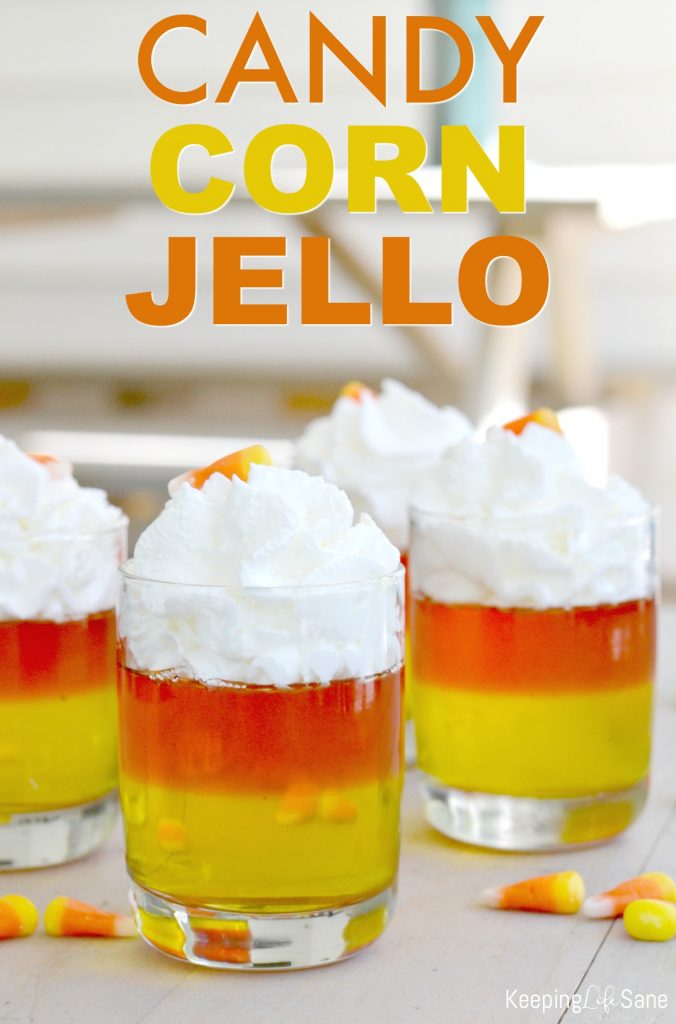 candy corn jello cups with yellow and orange jellos with whipped cream on top in clean glasses