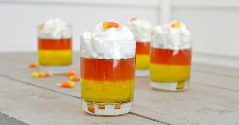 candy corn jello cups with yellow and orange jellos with whipped cream on top in clean glasses