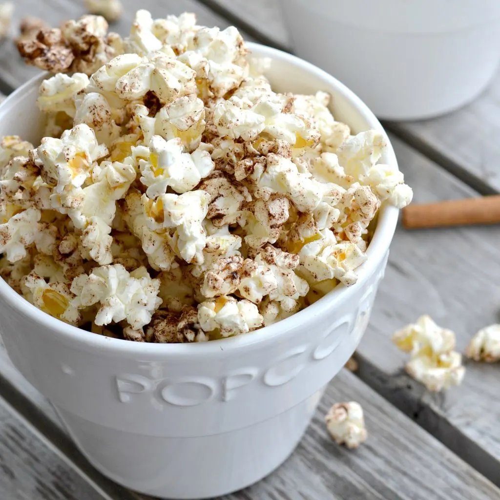 white popcorn bowl with cinnamon honey popcorn overflowing