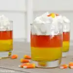 candy corn jello cups with yellow and orange jellos with whipped cream on top in clean glasses