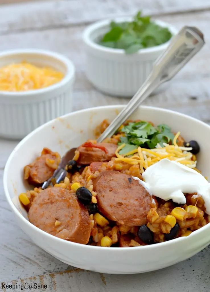 Mexican sausage casserole recipe in white bowl toppings in background