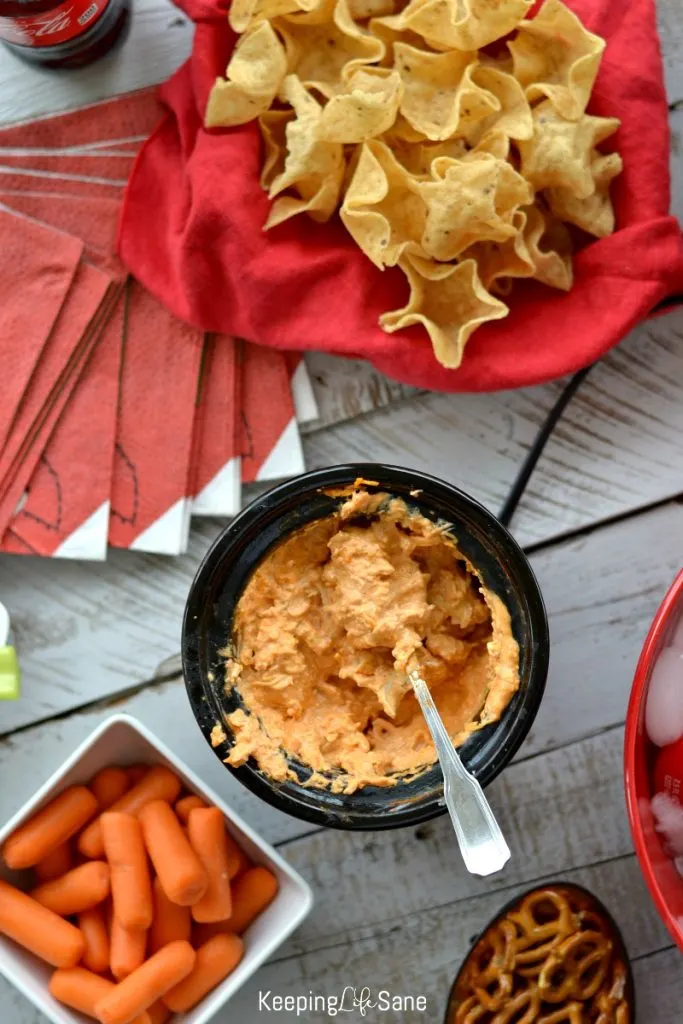 overhead view of buffalo chicken dip with tortilla chips, carrots, and pretzsels on the side