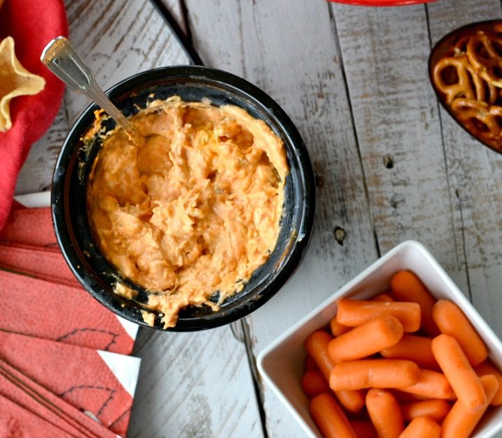 Overhead view of mini slow cooker with buffalo chicken dip with carrots, celery, pretzels and chips on the side