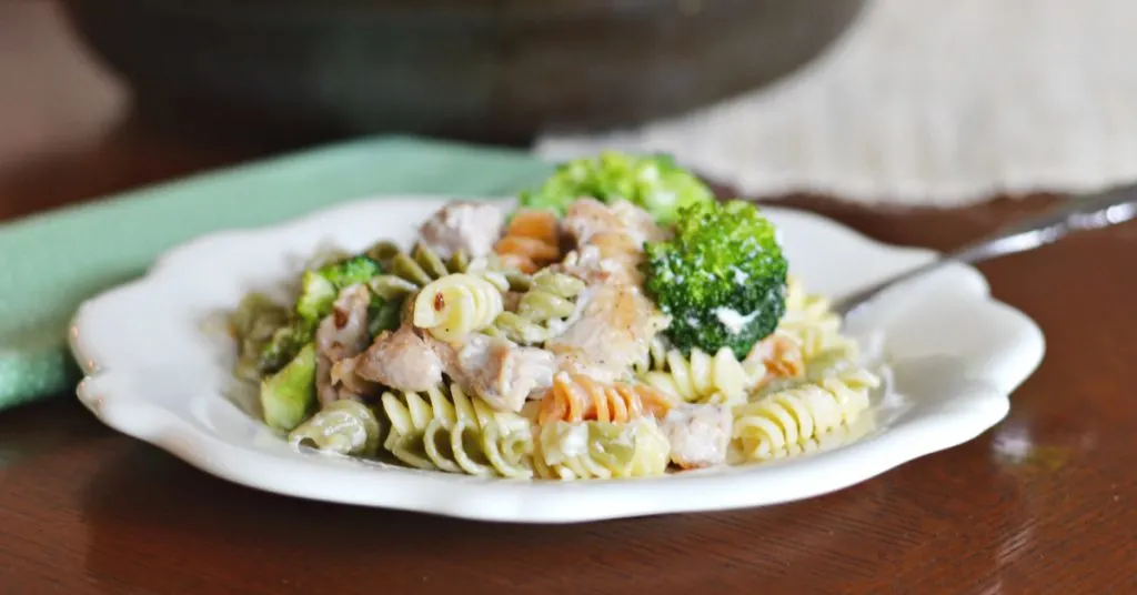 small white plate with tricolored rotini pasta, broccoli and chicken