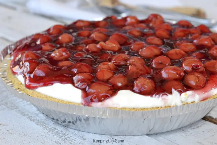 overhead view of cherry cream cheese pie with cherries on top on wooden table