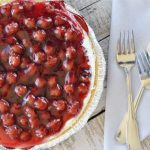 overhead view of cherry cream cheese pie with cherries on top on wooden table