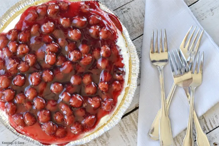 overhead view of cherry cream cheese pie with cherries on top on wooden table