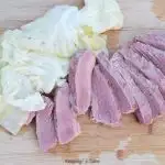 sliced corn beef on a cutting board with cabbage