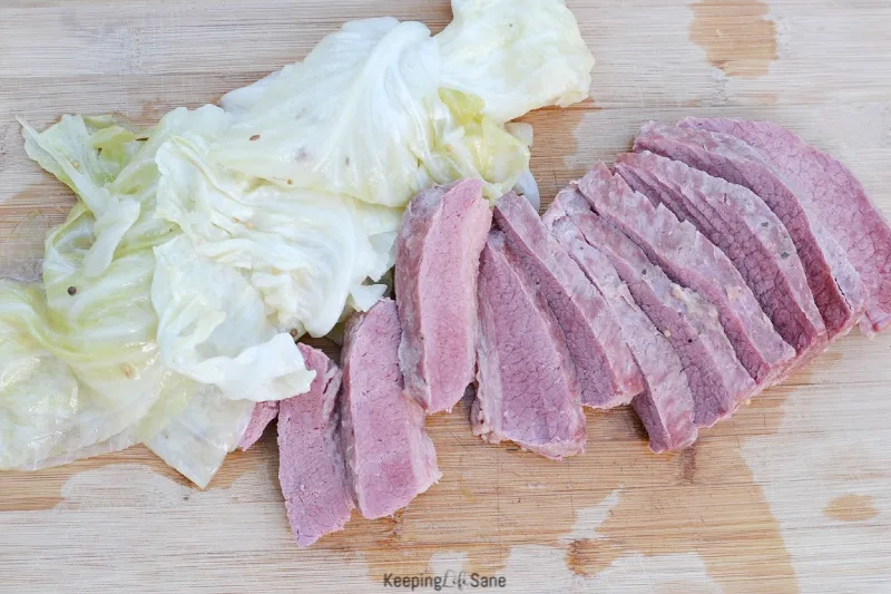 sliced corn beef on a cutting board with cabbage