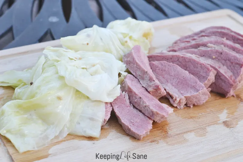 sliced corn beef on a cutting board with cabbage
