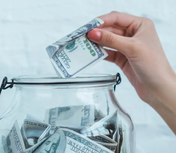 hand putting money in glass bowl