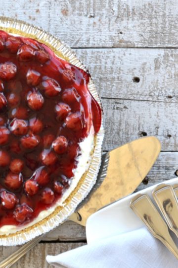 overhead view of cherry cream cheese pie with cherries on top on wooden table