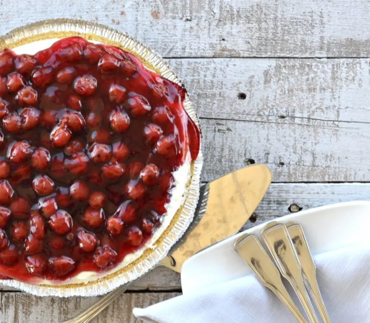 overhead view of cherry cream cheese pie with cherries on top on wooden table