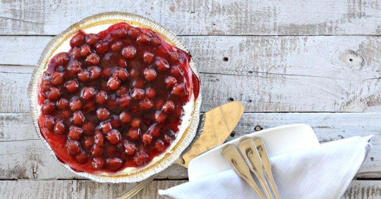 overhead view of cherry cream cheese pie with cherries on top on wooden table
