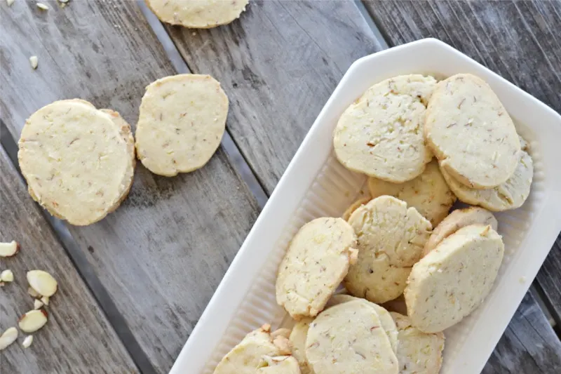 overhead view of almond shortbread cookies on a white platter on wooden table